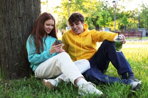 Two teens sitting together talking and laughing, showing trust and connection.
